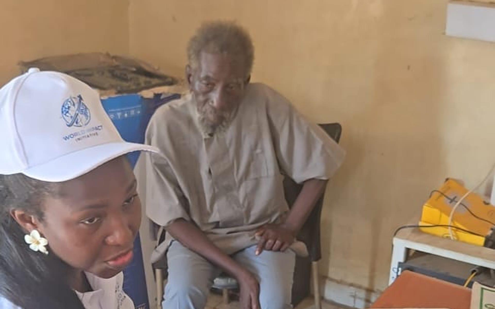 A team member speaking with an elderly beneficiary during a needs assessment