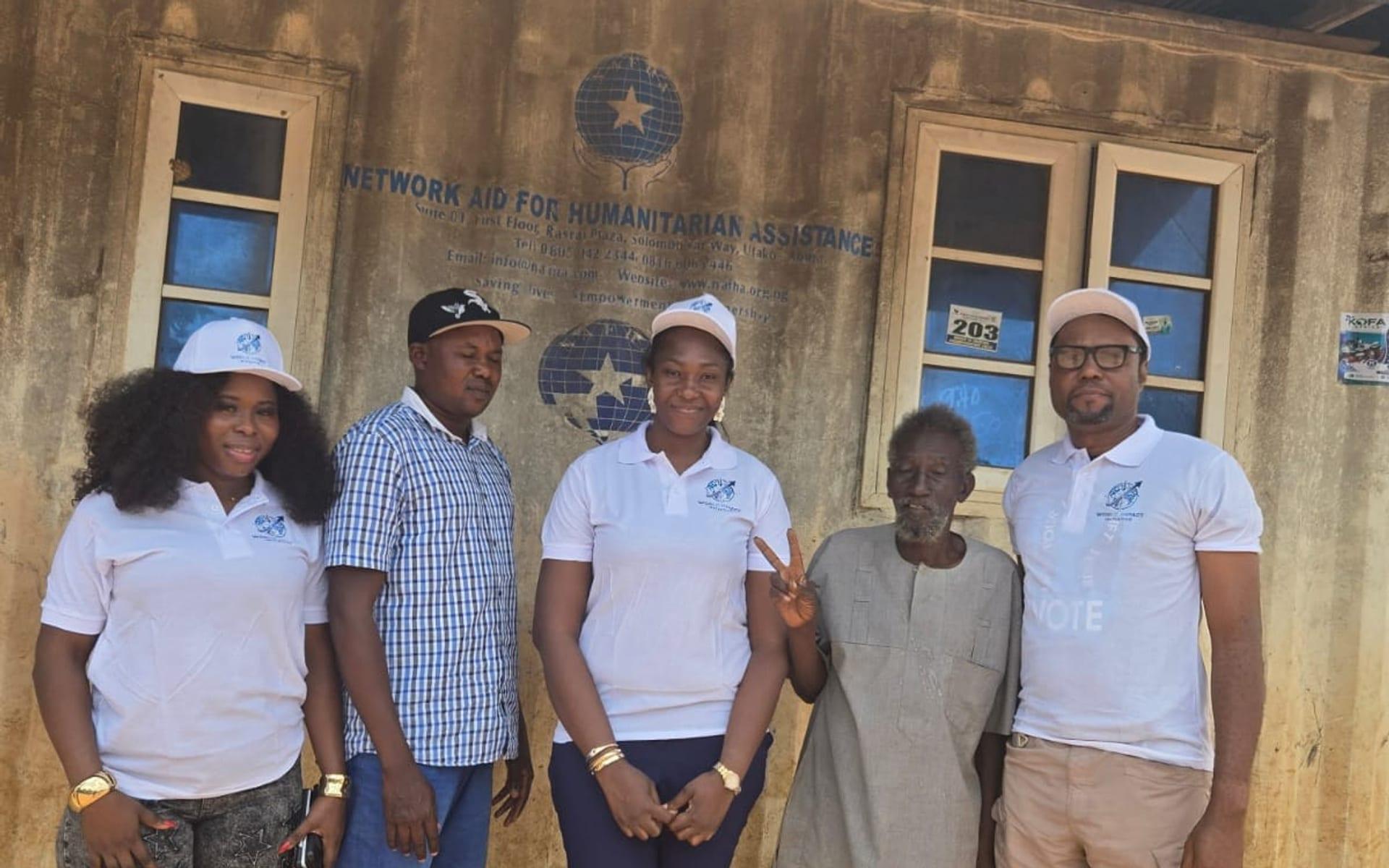 World Impact Initiative team standing with a community elder outside a partner aid office