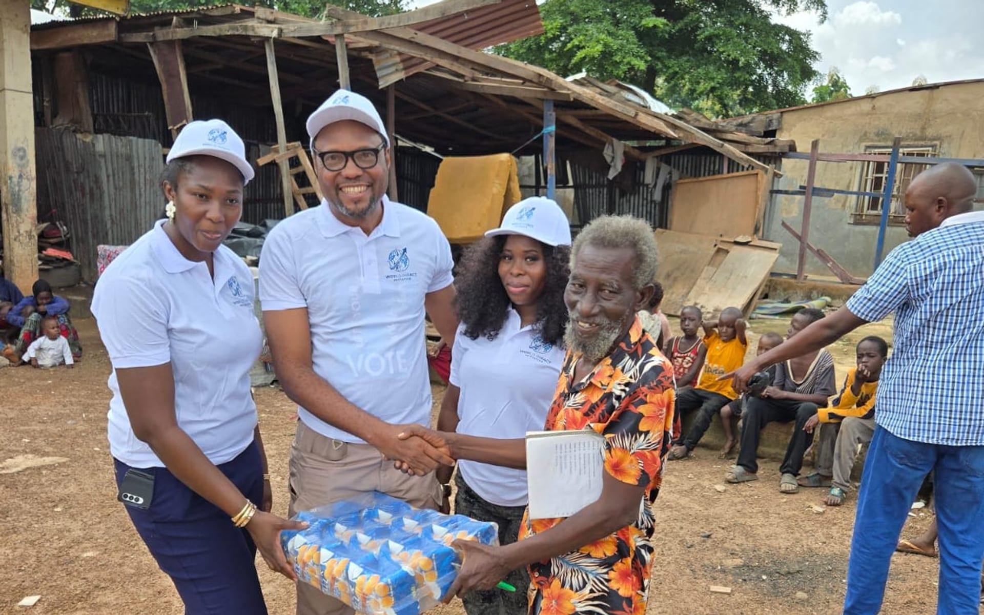 Team members handing relief supplies to a community elder and shaking his hand