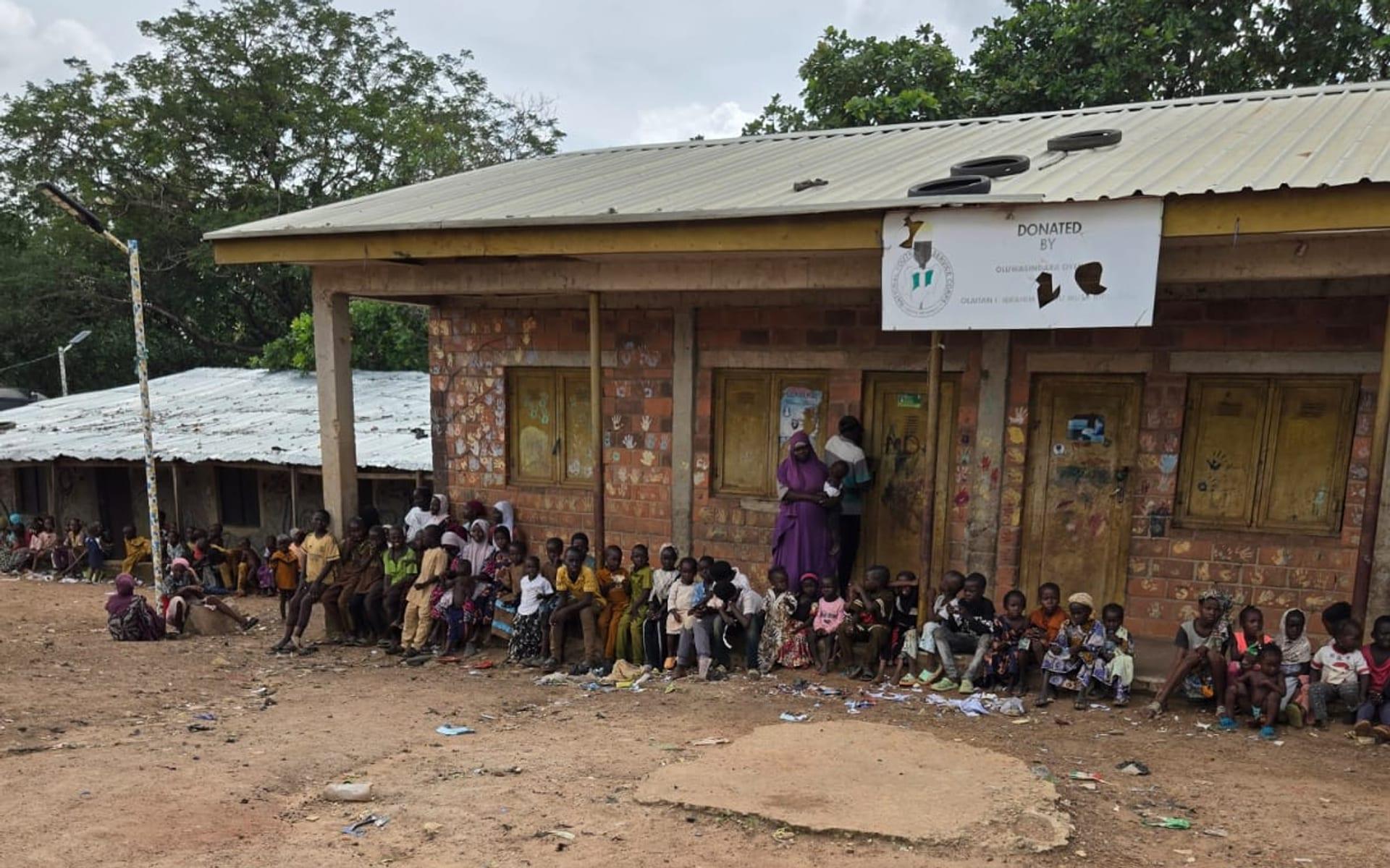 Schoolchildren gathered along the veranda of a community school building